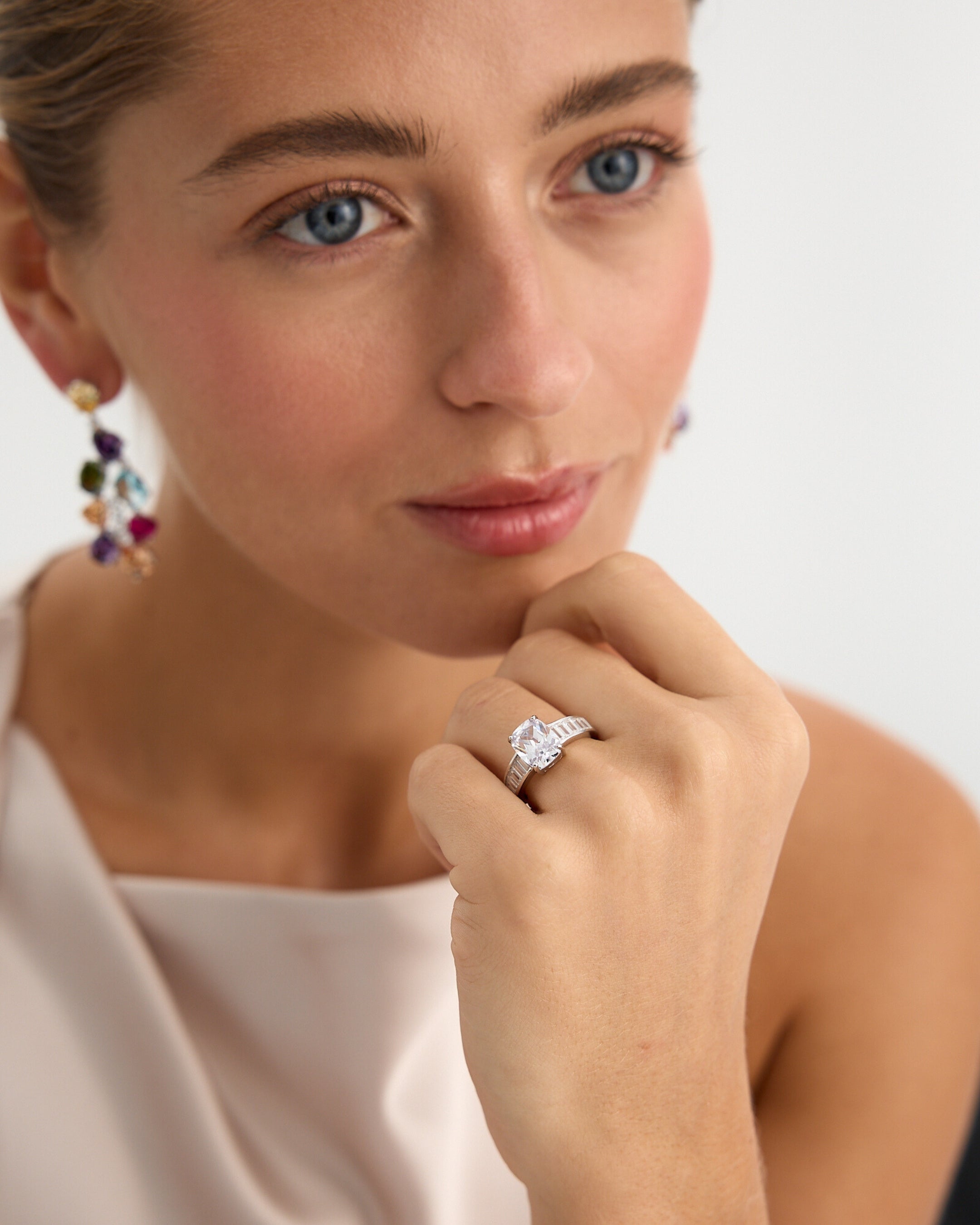 Anillo Éclair, elaborado en plata de ley 925 con baño de rodio blanco. Su diseño sofisticado presenta una piedra central blanca en talla cojín rectangular de 8x10 mm, engastada con elegancia en cuatro garras. Las piedras blancas laterales en talla baguette añaden un toque de luminosidad a los hombros del anillo. Una joya perfecta para quienes buscan distinción y brillo en cada detalle, ideal para cualquier ocasión especial.