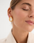 Los pendientes Pearl, inspirados en los elegantes collares de perlas de la era del jazz, combinan lujo y modernidad. Fabricados en plata de ley 925 con un baño de oro amarillo de 18 quilates, estos pendientes destacan por su delicada perla de nácar en talla gota como piedra principal. Con una longitud de 30 mm y cierre de tuerca, son perfectos para quienes buscan una pieza sofisticada y atemporal, ideal para destacar en cualquier evento.